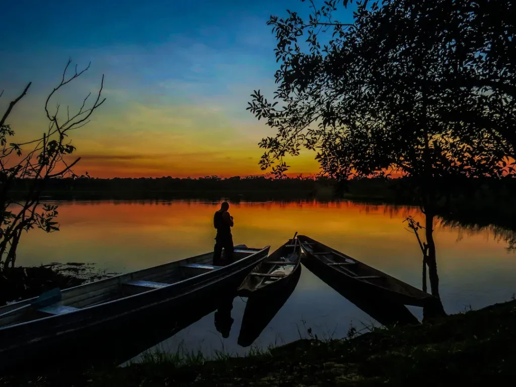 Silhouette of traveler at sunset on the Guayabero River with canoes in San José del Guaviare, Colombia